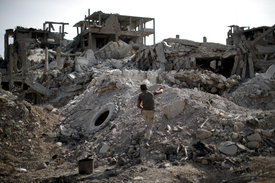 An young man walks through rubble in the Palestinian refugee camp of Yarmouk in the Syrian capital Damascus, Syria, Saturday, Oct. 6, 2018. The camp, once home to the largest concentration of Palestinians outside the territories housing nearly 160,000 people, has been gutted by years of war. (AP Photo/Hassan Ammar)