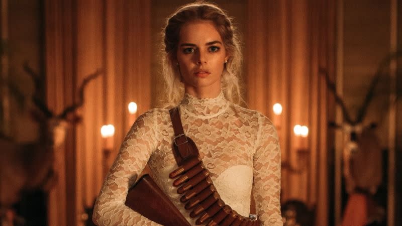 a woman stands in a wedding dress holding a rifle with ammo across her chest in a scene from ready or not, a good housekeeping pick for best halloween movies