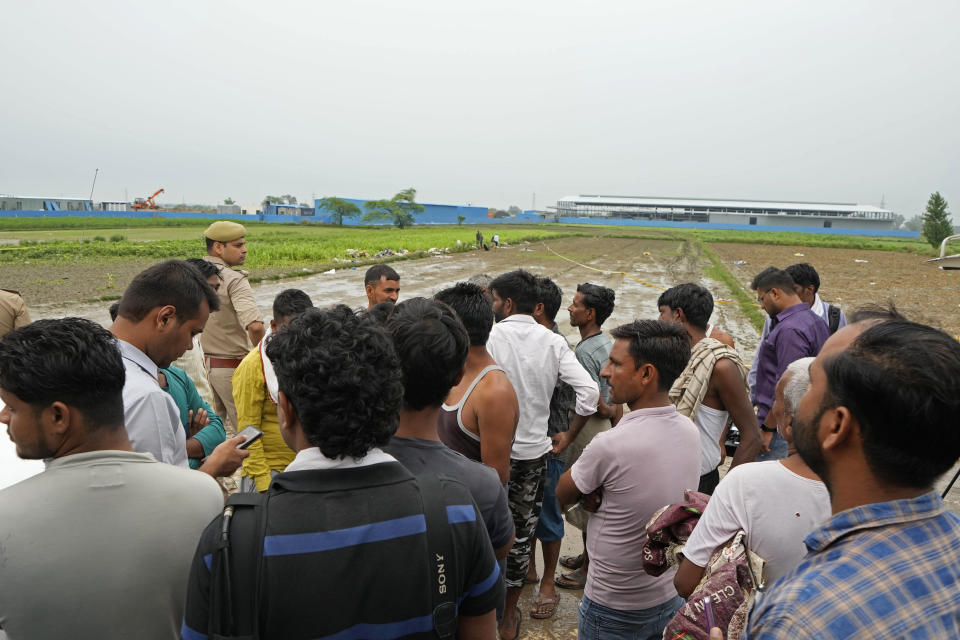 People watch members of a forensic team investigate the scene a day after a fatal stampede, in Fulrai village of Hathras district, Uttar Pradesh, India, Wednesday, July 3, 2024. Thousands of people at a religious gathering rushed to leave a makeshift tent, setting off a stampede Tuesday that killed more than hundred people and injured scores. (AP Photo/Rajesh Kumar Singh)