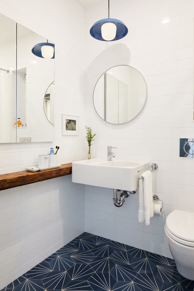 After: Sarah and her team added a lot of brightness with the white sink and tile work, and stainless steel fixtures, but still added a punch of fun with the starburst flooring and blue pendant light.