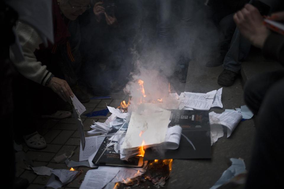 Pro-Russian activists burn security documents seized when mobs stormed the Ukrainian regional office of the Security Service in Donetsk, eastern Ukraine, Saturday, May 3, 2014, which has been captured to honor the memory of fallen comrades during fighting with pro-Ukrainian activists in Odessa on Friday. In Donetsk, the largest city in the insurgent east, demonstrators who stormed the local office of the Ukrainian Security Service on Saturday evening shouted "We will not forgive Odessa." No police were deployed to block the building takeover. (AP Photo/Alexander Zemlianichenko)
