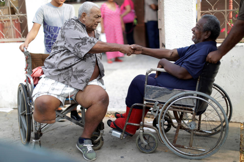Elimenes Fuenmayor, 65, a patient with kidney disease, greets another kidney disease patient as they wait for the electricity to return during a blackout, in front of a dialysis center in Maracaibo, Venezuela. (Photo: Ueslei Marcelino/Reuters)