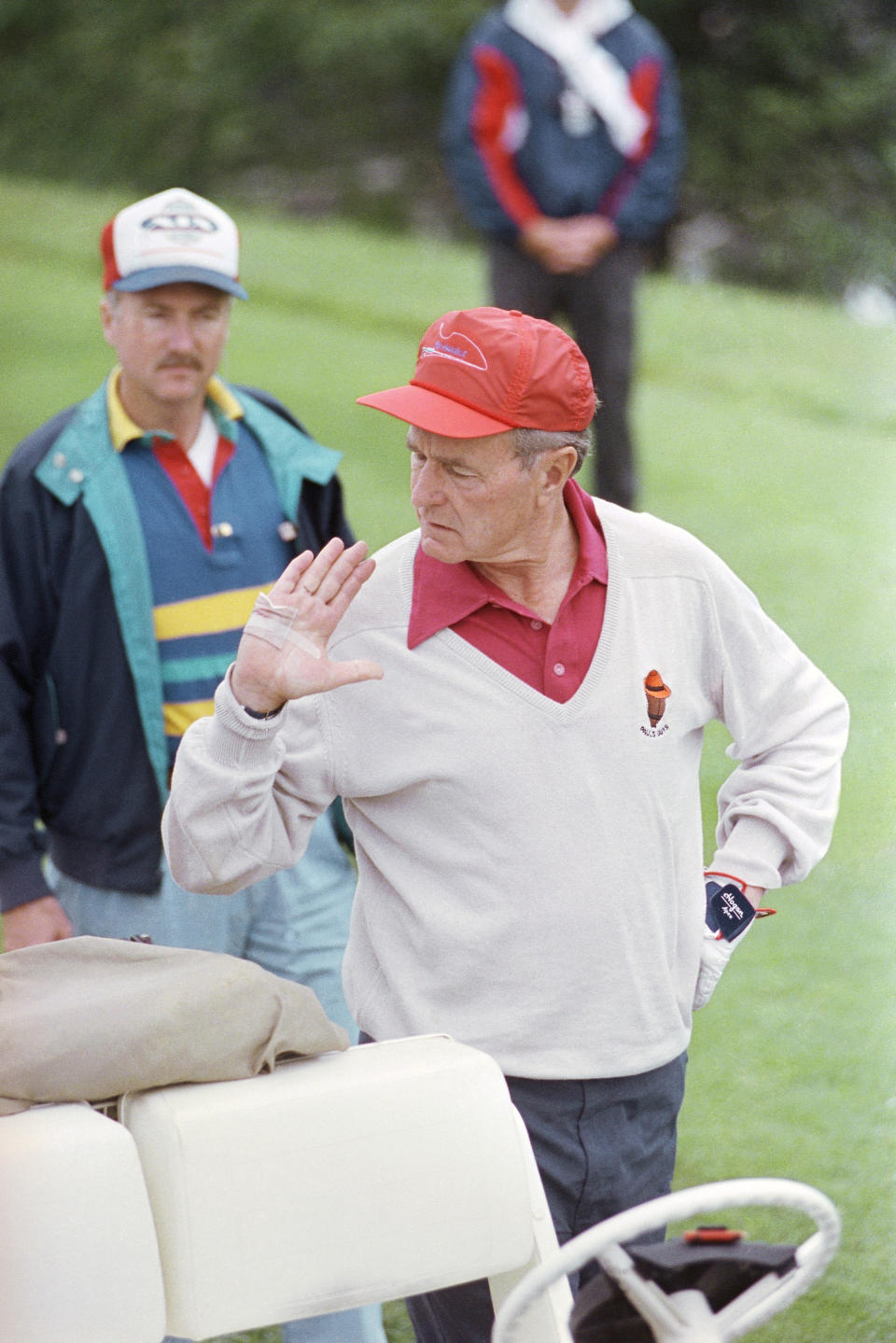 FILE - President George H.W. Bush checks his bandaged hand before starting a round of gold at the Cape Arundel Golf Club in Kennebunkport, Maine on July 4, 1990. The president said he cut his hand while cleaning fish he caught the day before. (AP Photo/Ron Edmonds, File)