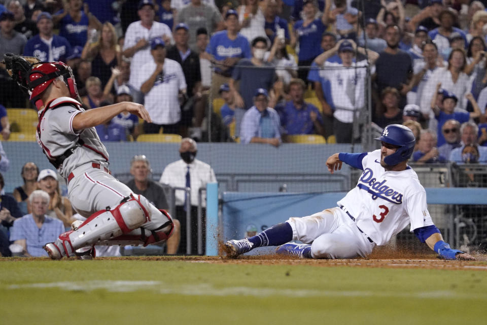 Los Angeles Dodgers' Chris Taylor, right, scores on a single by Zach McKinstry as Philadelphia Phillies catcher J.T. Realmuto misses the ball during the fourth inning of a baseball game Tuesday, June 15, 2021, in Los Angeles. (AP Photo/Mark J. Terrill)