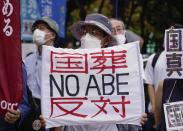A protester holds a sign opposing the state funeral of former Prime Minister Shinzo Abe at a protest in Tokyo, Tuesday, Sept. 27, 2022. (AP Photo/Christopher Jue)