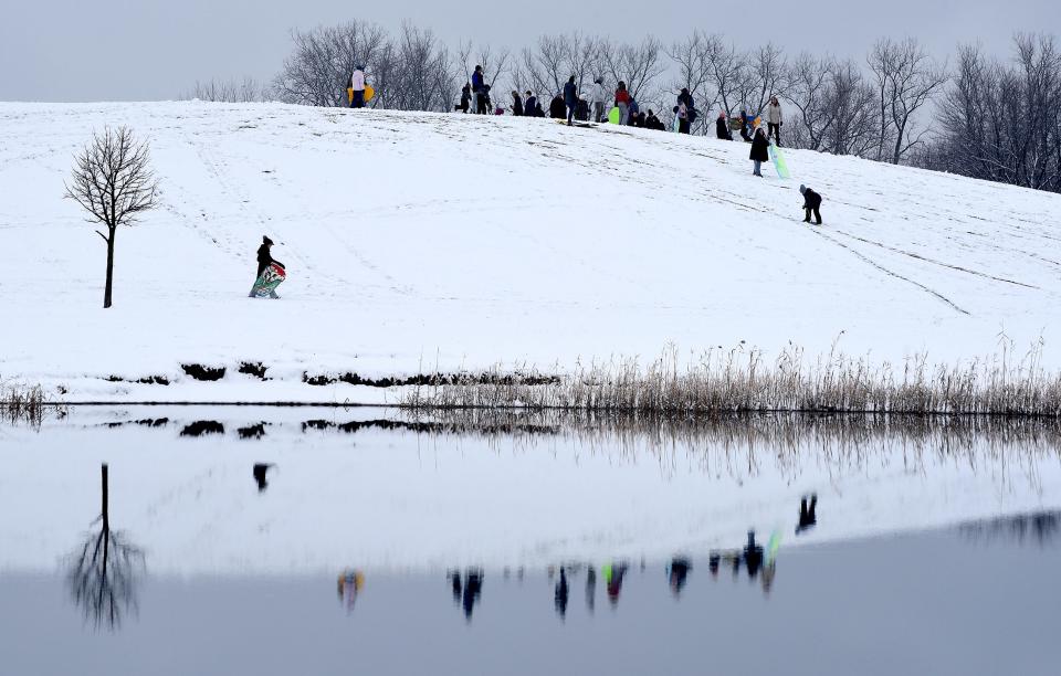 The recent snow fall Sunday, January 22, 2023 with warmer temperatures created this pictorial image of the sledders having fun on the hill at Munson Park but also reflections in the pond that is not frozen.