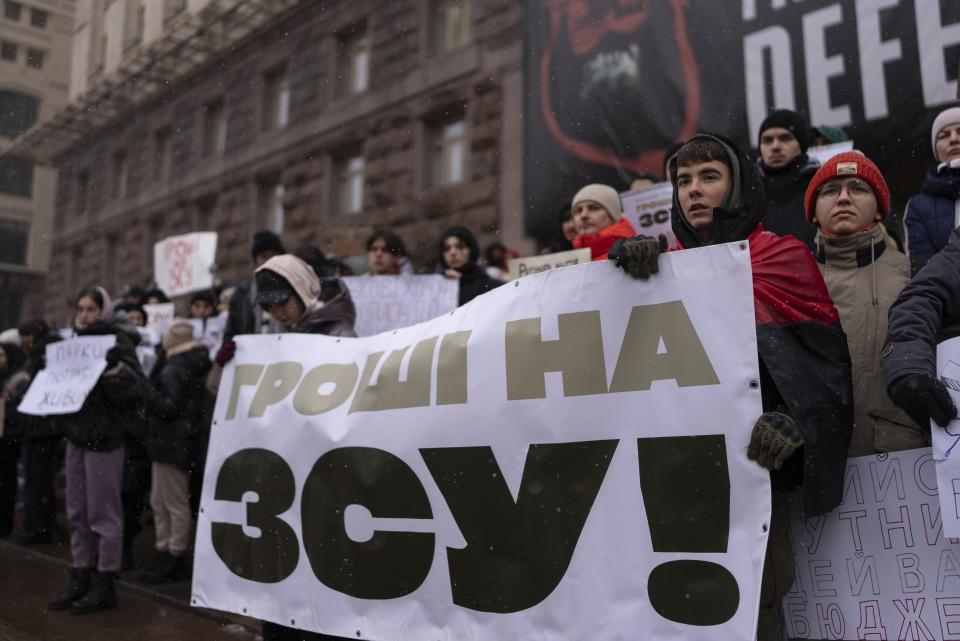 Misha Soboliev, second from right, holds a banner reading "Money to the Armed Forces of Ukraine, in central Kyiv, Ukraine, on Dec. 2, 2023. (AP Photo/Alex Babenko)