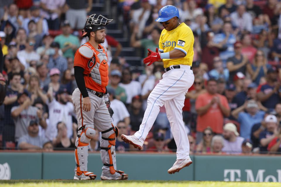 Boston Red Sox's Rafael Devers, right, celebrates in front of Baltimore Orioles' Austin Wynns after scoring on a single by Xander Bogaerts during the fifth inning of a baseball game, Saturday, Sept. 18, 2021, in Boston. (AP Photo/Michael Dwyer)