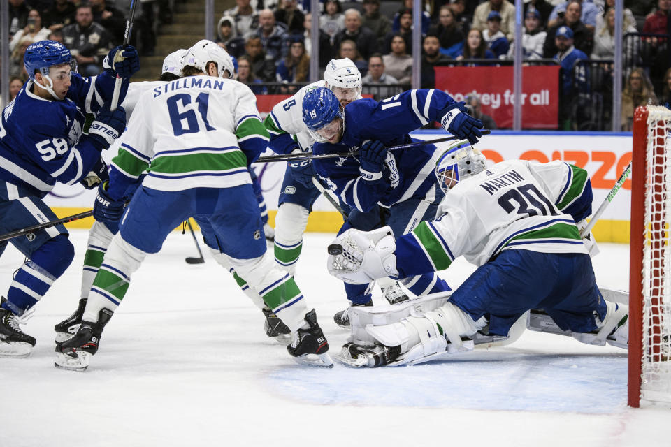 Vancouver Canucks goaltender Spencer Martin (30) defends against an attack on net by Toronto Maple Leafs center Calle Jarnkrok (19) and left wing Michael Bunting (58) during the second period of an NHL hockey game in Toronto, Saturday, Nov. 12, 2022. (Christopher Katsarov/The Canadian Press via AP)