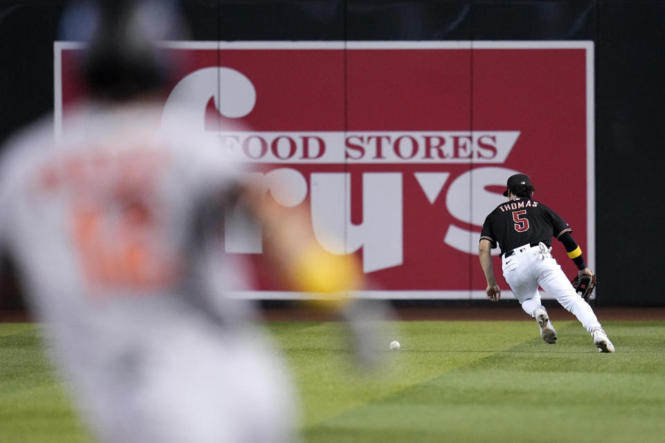 Arizona Diamondbacks center fielder Alek Thomas (5) lets the ball gets past him for an error on a single hit by Baltimore Orioles' Adam Frazier, left, allowing Frazier to advance to second base during the fourth inning of a baseball game Sunday, Sept. 3, 2023, in Phoenix. (AP Photo/Ross D. Franklin)