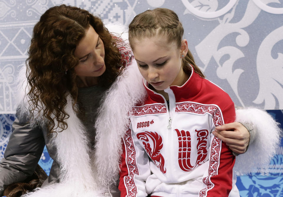 Julia Lipnitskaya of Russia, right, and her coach Eteri Tutberidze wait in the results area after she completed her routine in the women's short program figure skating competition at the Iceberg Skating Palace during the 2014 Winter Olympics, Wednesday, Feb. 19, 2014, in Sochi, Russia. (AP Photo/Bernat Armangue)