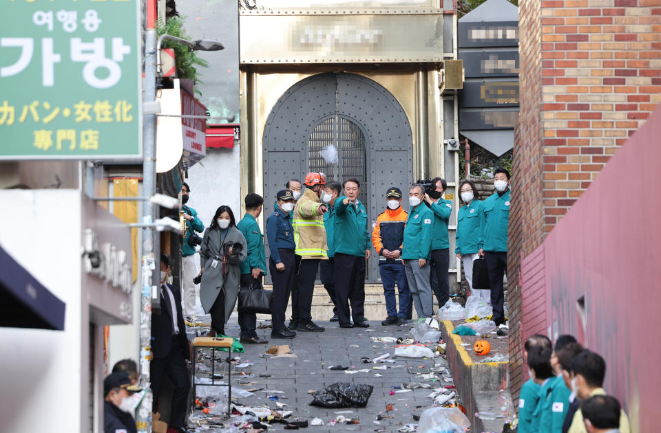 South Korean President Yoon Suk Yeol, center, visits the scene where dozens of people died and were injured in Seoul, South Korea, Sunday, Oct. 30, 2022, after a mass of mostly young people celebrating Halloween festivities became trapped and crushed as the crowd surged into a narrow alley. (Han Sang-gyun/Yonhap via AP)