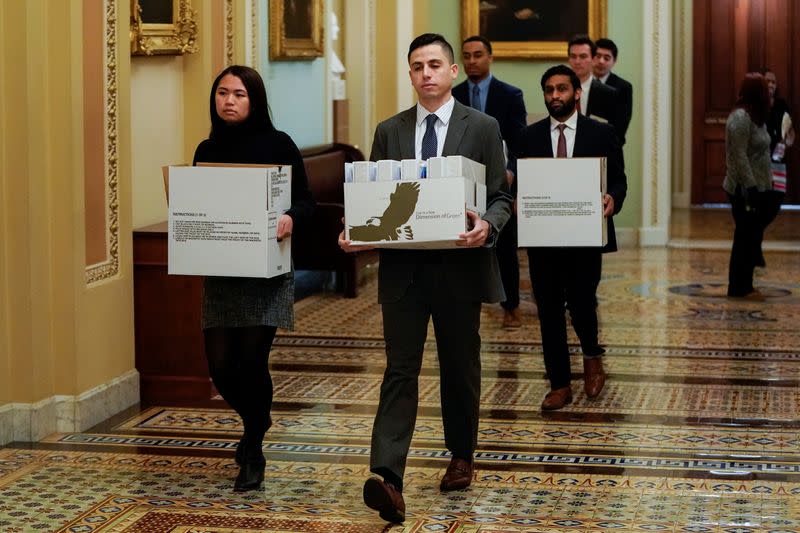 Staffers carry boxes of documents to Senate Minority Leader Schumer's office the first day of the Trump impeachment in Washington.