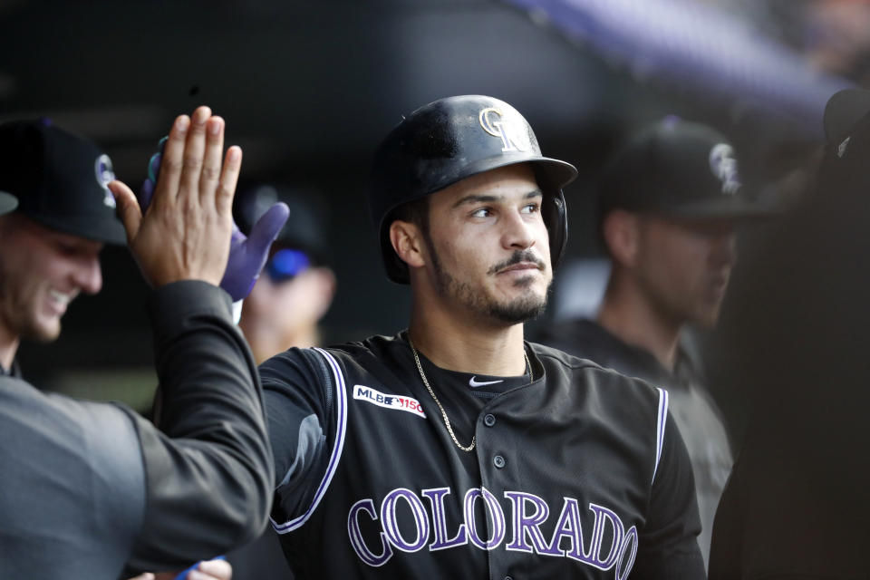 Colorado Rockies' Nolan Arenado is congratulated as he returns to the dugout after hitting a solo home run off Baltimore Orioles starting pitcher John Means in the first inning of a baseball game Friday, May 24, 2019, in Denver. (AP Photo/David Zalubowski)