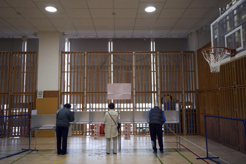Voters prepare to cast their ballots in the lower house elections as representatives of a local election administration commission observes at a polling station Sunday, Oct. 31, 2021, in Tokyo. (AP Photo/Eugene Hoshiko)