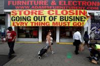 FILE PHOTO: People walk by a store going out of business along 125th street in the Harlem neighborhood of New York City