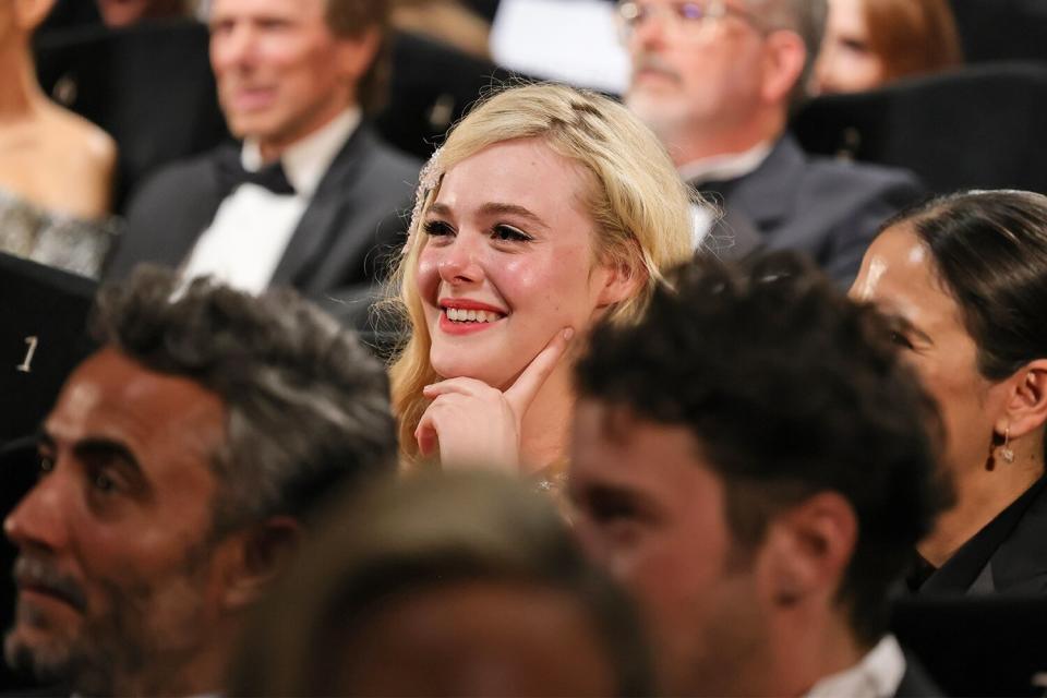 Elle Fanning reacts as Tom Cruise receives a Palme d'Or during the 75th annual Cannes film festival at Palais des Festivals on May 18, 2022 in Cannes, France.