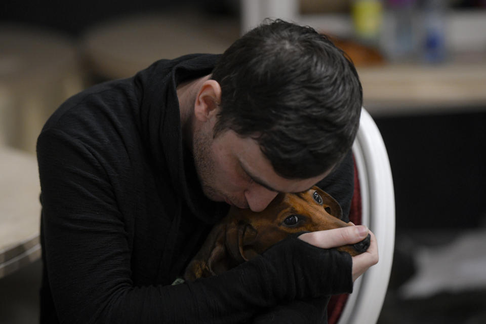 A refugee who fled the Russian invasion from neighboring Ukraine comforts his dog as they sit in a ballroom converted into a makeshift refugee shelter at a 4-star hotel & spa, in Suceava, Romania, Friday, March 4, 2022. (AP Photo/Andreea Alexandru)