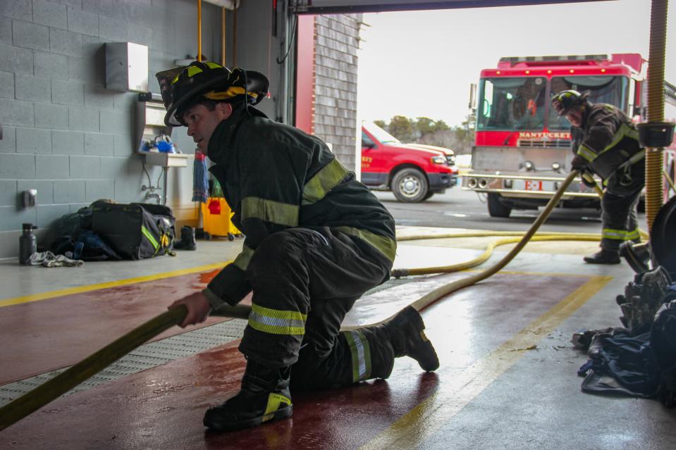 Fall River firefighters Jason Burns and C.J. Ponte drag a full hose into the apparatus bay as part of a training and research exercise into firefighters and PFAS exposure at Nantucket Fire Department headquarters on March 28, 2022.