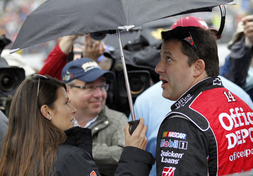 Tony Stewart, right, and Danica Patrick, left, stand under an umbrella during a rain delay in the start of the NASCAR Daytona 500 Sprint Cup series auto race in Daytona Beach, Fla., Sunday, Feb. 26, 2012. (AP Photo/Terry Renna)