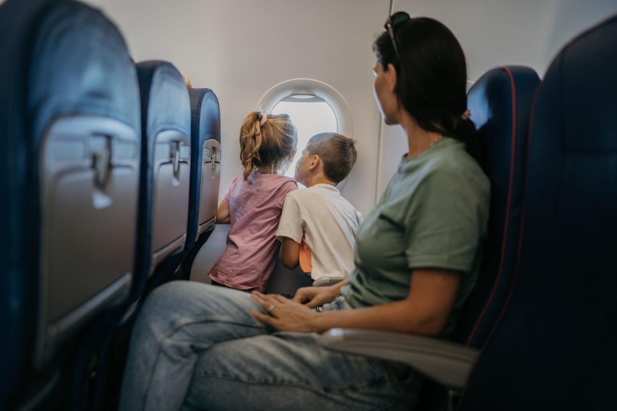 Mother with two children, son and daughter  traveling by plane, kids are looking through window