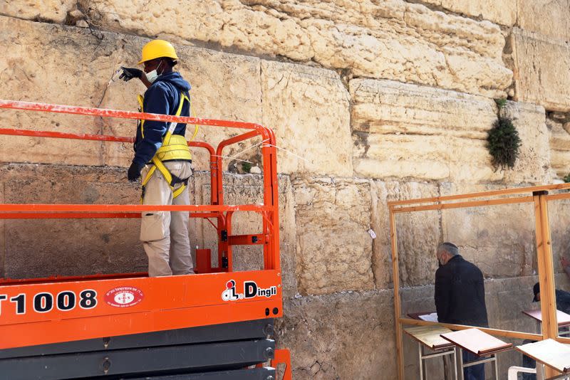 A labourer stands on a portable lift as he injects a type of grout into gaps and fissures in the stones of the Western Wall, Judaism's holiest prayer site, as part of the Israel Antiquities Authority treatment of the ancient stones, in Jerusalem's Old City