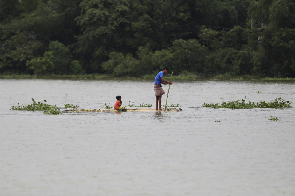 A man and a child travel on a wooden plank through flood waters in Bagha area in Sylhet, Bangladesh, Monday, May 23, 2022. Pre-monsoon deluges have flooded parts of India and Bangladesh, killing at least 24 people in recent weeks and sending 90,000 people into shelters, authorities said Monday. (AP Photo)