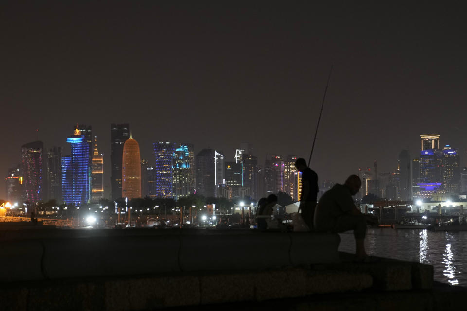 FILE - With Doha skyline in the background, a man prepares to casts his fishing pole at the Corniche waterfront promenade in Doha, Qatar, Nov. 11, 2022. Qatar unveiled a plan last October to cut its emissions by a quarter by 2030. Then, Russia invaded Ukraine and made the Persian Gulf nation's liquid natural gas only more sought after. Demand for fossil fuels has brought immense wealth to Qatar, but in the coming decades, it could also make one of the world's hottest places unlivable. (AP Photo/Hassan Ammar, File)