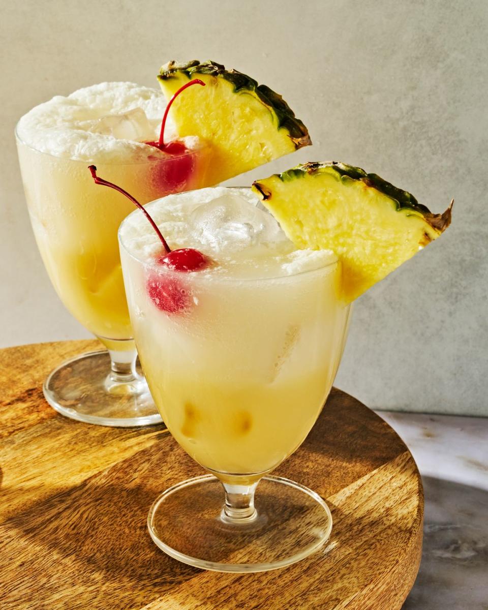 pina colada spritz topped with a maraschino cherry and a pineapple wedge