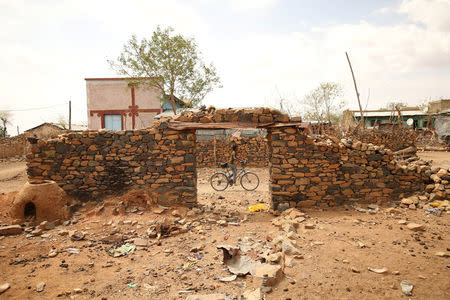 A boy rides a biycle past damaged houses during Ethiopia-Eritrea war fought between 1998 to 2000 in Badme, territorial dispute town between Eritrea and Ethiopia currently occupied by Ethiopia, June 8, 2018. Picture taken June 8, 2018. REUTERS/Tiksa Negeri