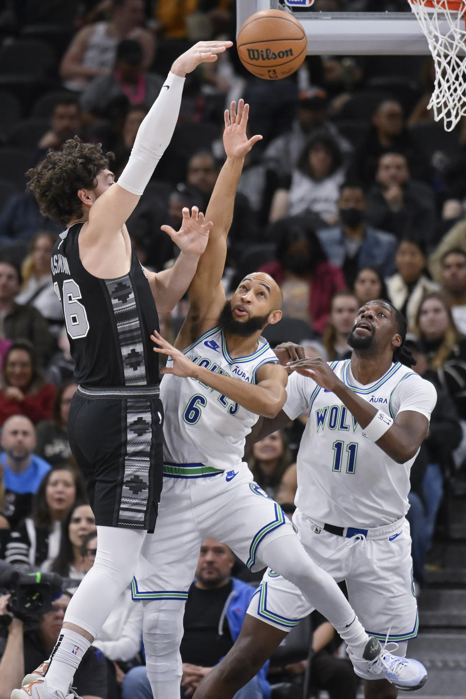 San Antonio Spurs' Cedi Osman, left, passes the ball over Minnesota Timberwolves' Jordan McLaughlin (6) and Naz Reid during the first half of an NBA basketball game Saturday, Jan. 27, 2024, in San Antonio. (AP Photo/Darren Abate)