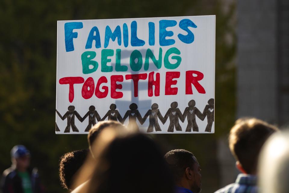 A person holds a sign reading "Families Belong Together" during the "Rally for Immigration Reform" on Saturday, Oct. 27, 2018, on the east side the Pentacrest in Iowa City.