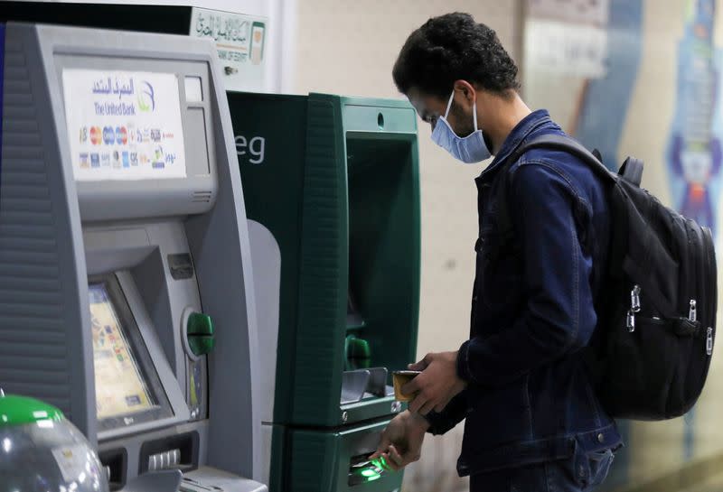 FILE PHOTO: A man wearing a protective face mask withdraws money from an ATM in Cairo