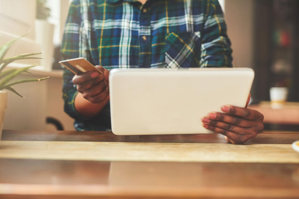 woman in cafe with tablet and holding credit card because you know she's about to buy something