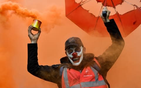  A man wearing a clown mask and waving a smoke bomb takes part in a demonstration to protest against the pension overhauls, in Marseille - Credit: CLEMENT MAHOUDEAU/AFP via Getty Images