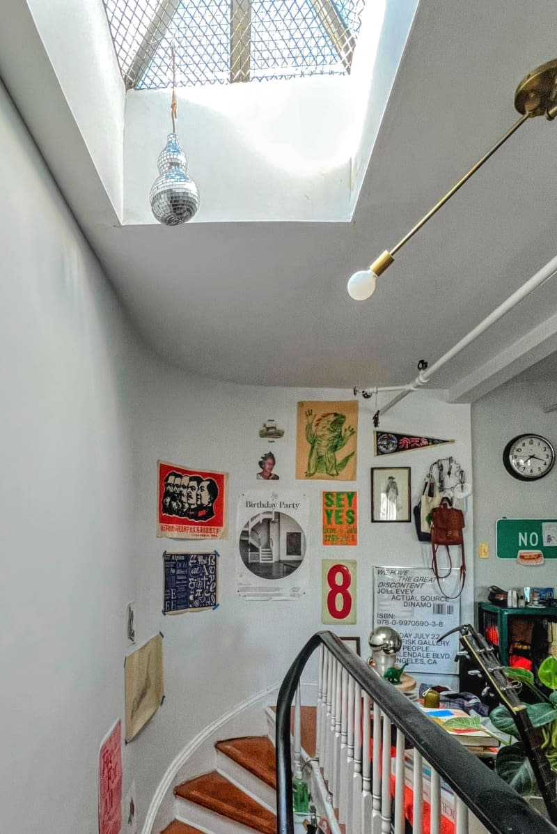 Decorative items are attached to a white wall next to a green cabinet with storage in a stairwell