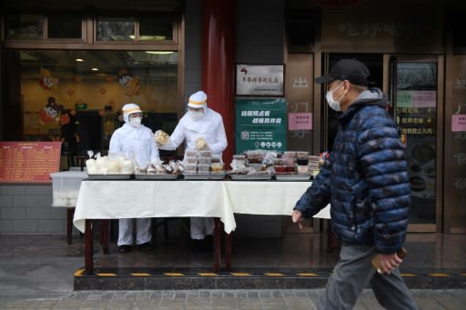 Restaurant workers wear protective clothing as they prepare food to sell on the street outside their restaurant in Beijing this week