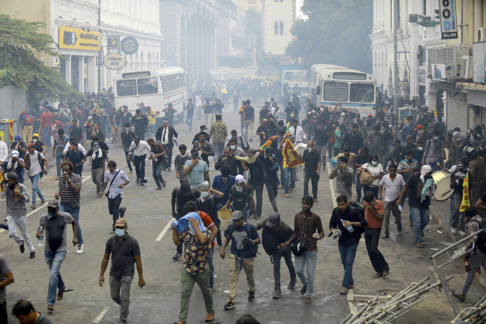 Protestors run after police used tear gas to disperse them in Colombo, Sri Lanka, Saturday, July 9, 2022. Sri Lankan protesters demanding that President Gotabaya Rajapaksa resign forced their way into his official residence on Saturday, a local television report said, as thousands of people took to the streets in the capital decrying the island nation's worst economic crisis in recent memory. (AP Photo/Amitha Thennakoon)