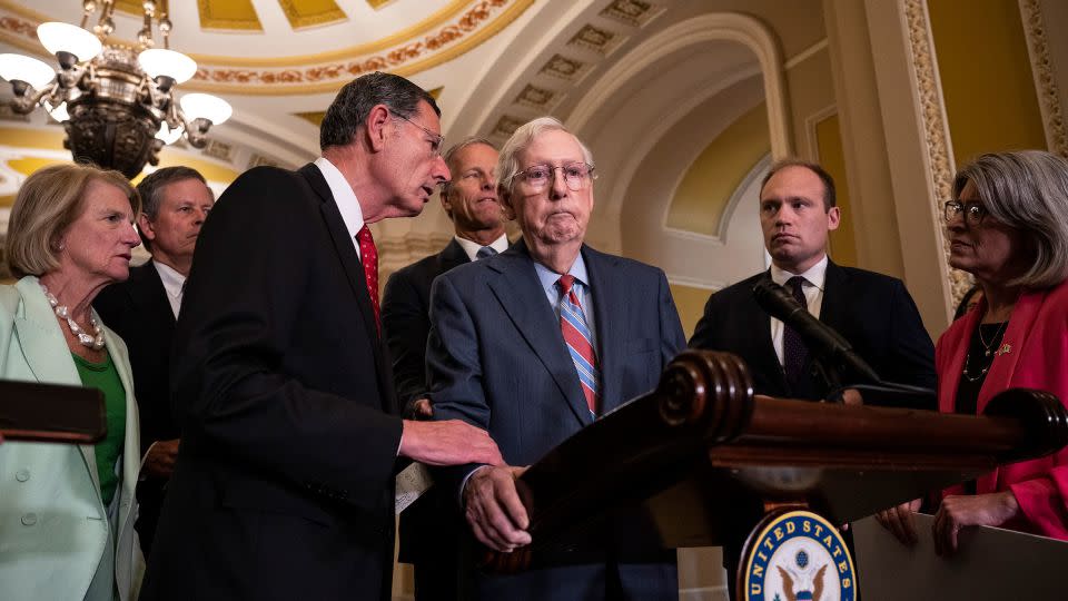 Sen. John Barrasso reaches out to help McConnell after McConnell froze and stopped talking during a news conference at the Capitol in July 2023. McConnell was led away from the news conference and toward his office by an aide. He returned a few minutes later and continued. - Drew Angerer/Getty Images