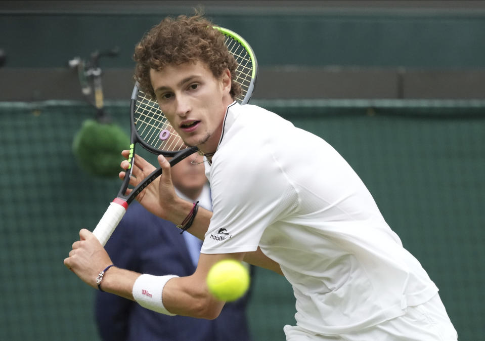 Ugo Humbert of France plays a return to Australia's Nick Kyrgios during the men's singles first round match on day three of the Wimbledon Tennis Championships in London, Wednesday June 30, 2021. (AP Photo/Alberto Pezzali)