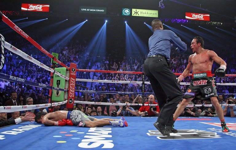 Referee Kenny Bayless (C) holds back Juan Manuel Marquez (R) as Manny Pacquiao lies face down on the canvas after being knocked out by Marquez at the MGM Grand Garden in Las Vegas. A bloodied Marquez rallied to knock out eight division champ Pacquiao with one second left in the sixth round and win the fourth fight of their epic boxing rivalry