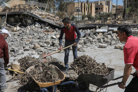 Workers clean debris of the remains of the University of Mosul. REUTERS/Marko Djurica