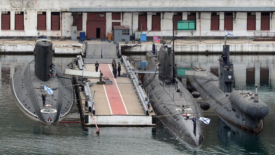 Russian navy sailors stand still during a flag-raising ceremony on a moorage near the Russian submarine B-871 Alrosa (L), stolen Ukrainian submarine ‘Zaporizhzhia’ and Russian Romeo Class Submarine PZS-50 (R) moored in the bay of the city of Sevastopol in the Russia-occupied Crimea, on April 2, 2014. (Photo by Olga Maltseva/AFP via Getty Images)