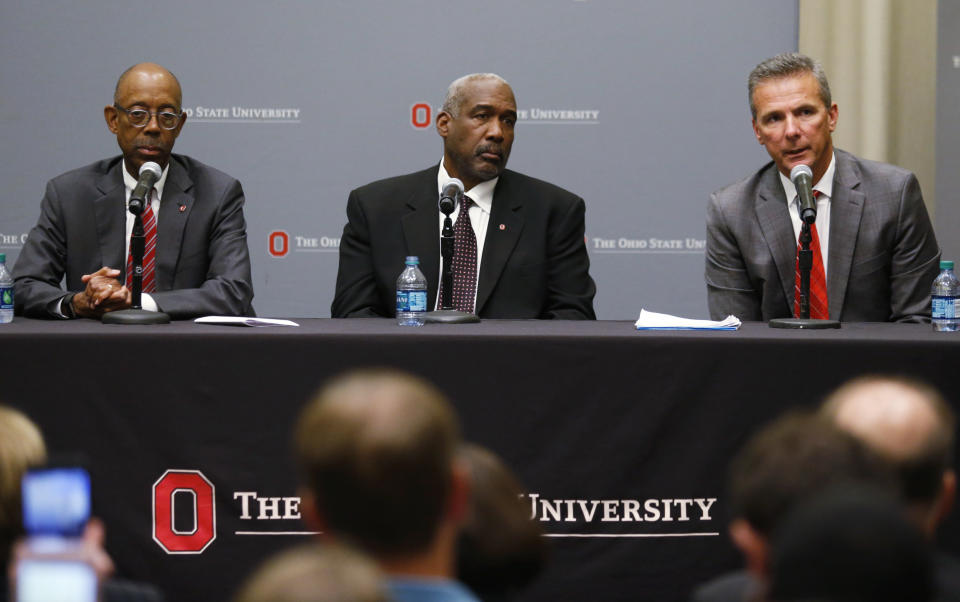 Ohio State football coach Urban Meyer, right, answers questions as athletic director Gene Smith and university President Michael Drake, left, listen during a news conference in Columbus, Ohio, Wednesday, Aug. 22, 2018. Ohio State suspended Meyer on Wednesday for three games for mishandling domestic violence accusations, punishing one of the sport's most prominent leaders for keeping an assistant on staff for several years after the coach's wife accused him of abuse. Gene Smith was suspended from Aug. 31 through Sept. 16. (AP Photo/Paul Vernon)