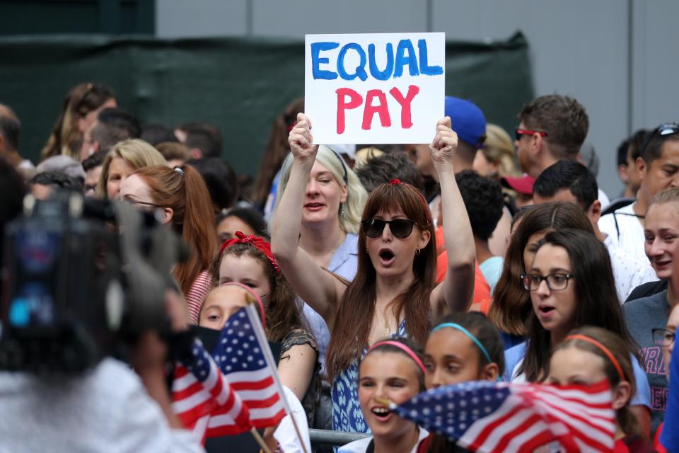 Fans along the parade route chant for equal pay as they wait for the United States women's national soccer team in July 2019