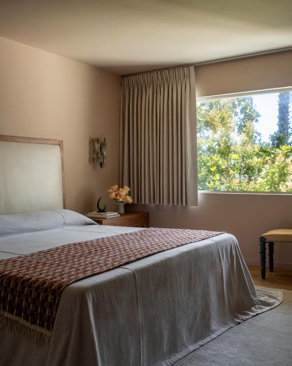 In the primary bedroom, vintage Murano glass sconces dazzle in the afternoon afterglow. The bed, crafted in leather and walnut wood, is a labor of love by Studio Muka. The rug is an Armadillo find.