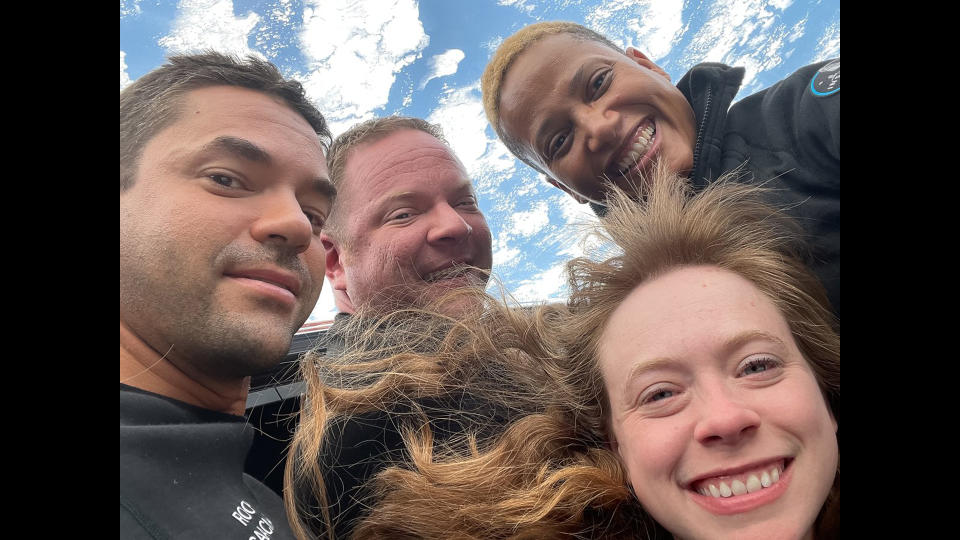 Four smiling people with Earth in the background.