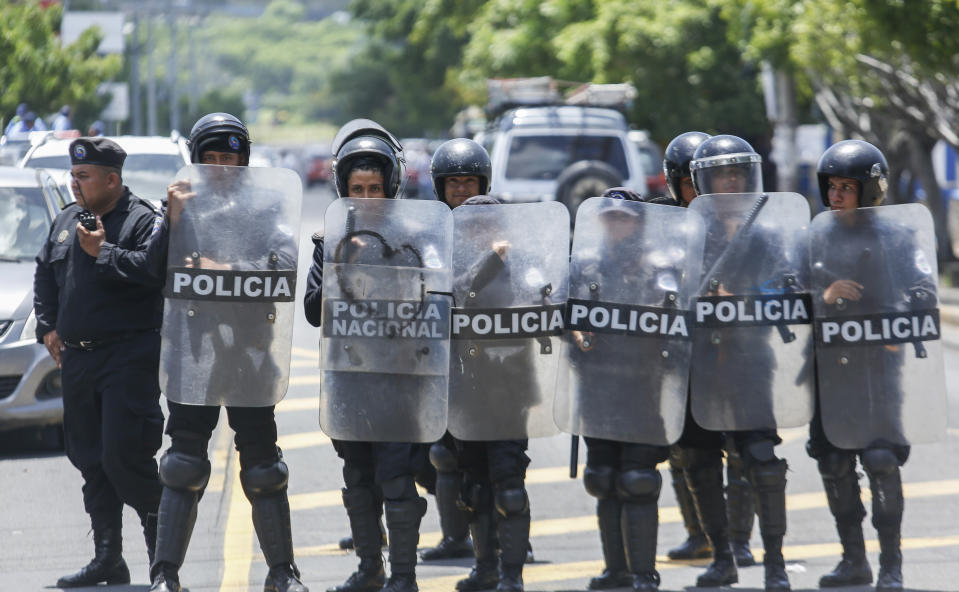 Police stand outside the Central American University (UCA), where they cannot legally enter, as they watch students protest inside the campus, demanding the release of all political prisoners on the last day of a 90-day period for releasing such prisoners, as agreed during negotiations between the government and opposition, in Managua, Nicaragua, Tuesday, June 18, 2019. Nicaragua's government said Tuesday that it has released all prisoners detained in relation to 2018 anti-government protests, though the opposition maintains that more than 80 people it considers political prisoners are still in custody. (AP Photo/Alfredo Zuniga)