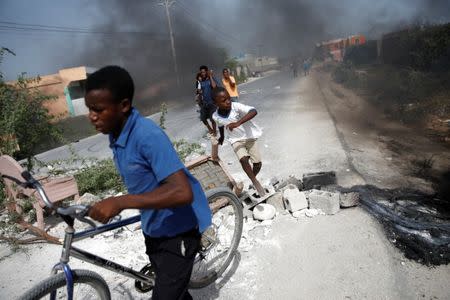 People pass through a barricade on the outskirts of Croix-des-Bouquets, Haiti, July 8, 2018. REUTERS/Andres Martinez Casares