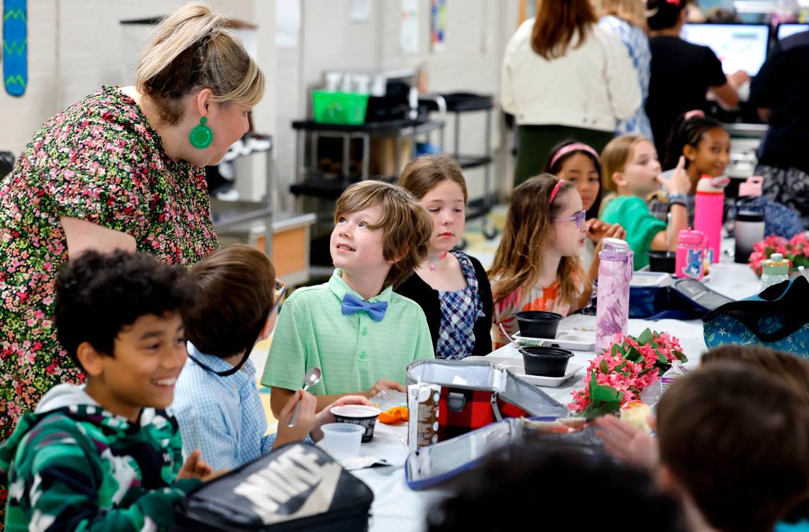 Combs Elementary School’s Traci Totherow talks with fourth grader Winston Eckerson during the Silver Tray lunch at Combs Elementary School in Raleigh, N.C., Thursday, May 16, 2024. At the Silver Tray Luncheon there is fancy silverware, cafeteria tables have tablecloths and centerpieces as the Enloe High School orchestra plays music to provide a fine dining experience. The dining experience was the culmination of a year-long effort to teach Combs’ students about the value of social etiquette and good manners.